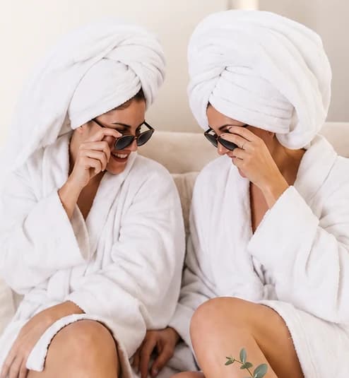 Friends in robes laughing together at an MK Wellness Spa Party